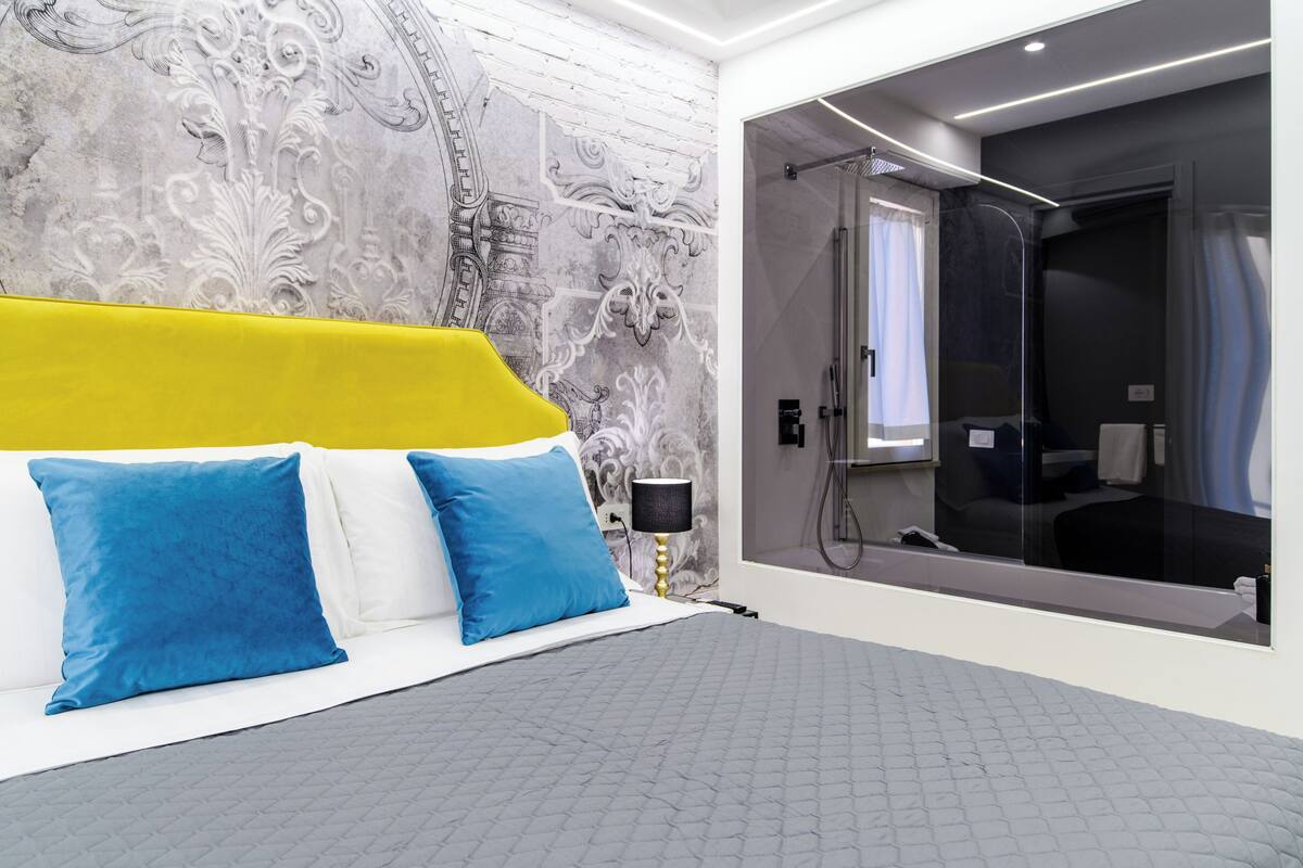 Quarto moderno com uma cama, chuveiro e um espelho grande.