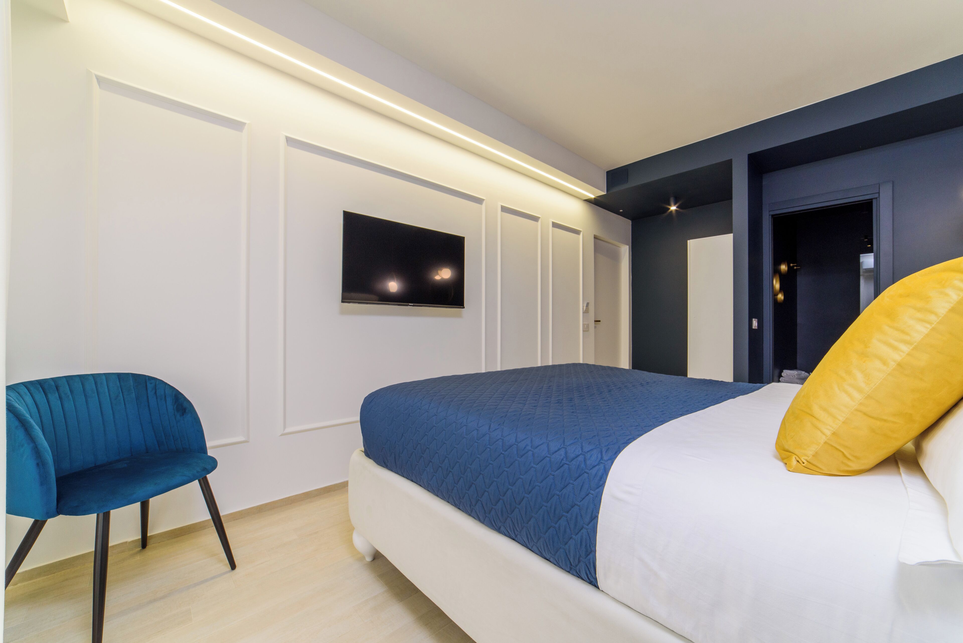 Une chambre à coucher moderne avec un lit, un téléviseur fixé au mur et une chaise.