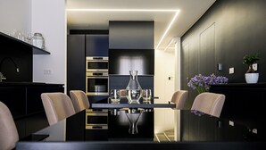 A modern dining area with a glass table, chairs, and a vase of flowers. - Shamika Luxury Rooms (Montecorvino Pugliano)