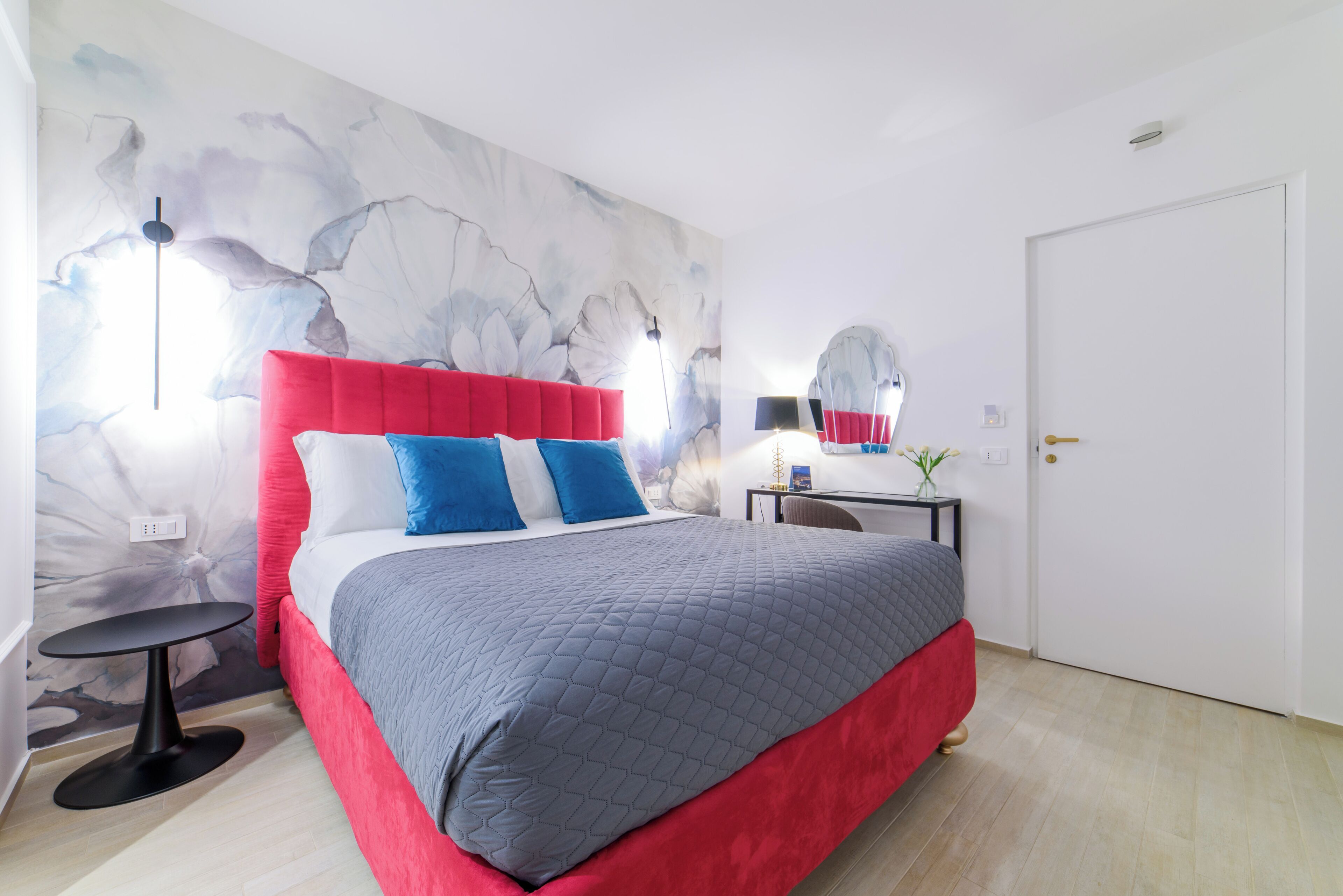 Un dormitorio moderno con un cabecero tapizado en rojo, una colcha acolchada gris y una pared con diseño de mármol.