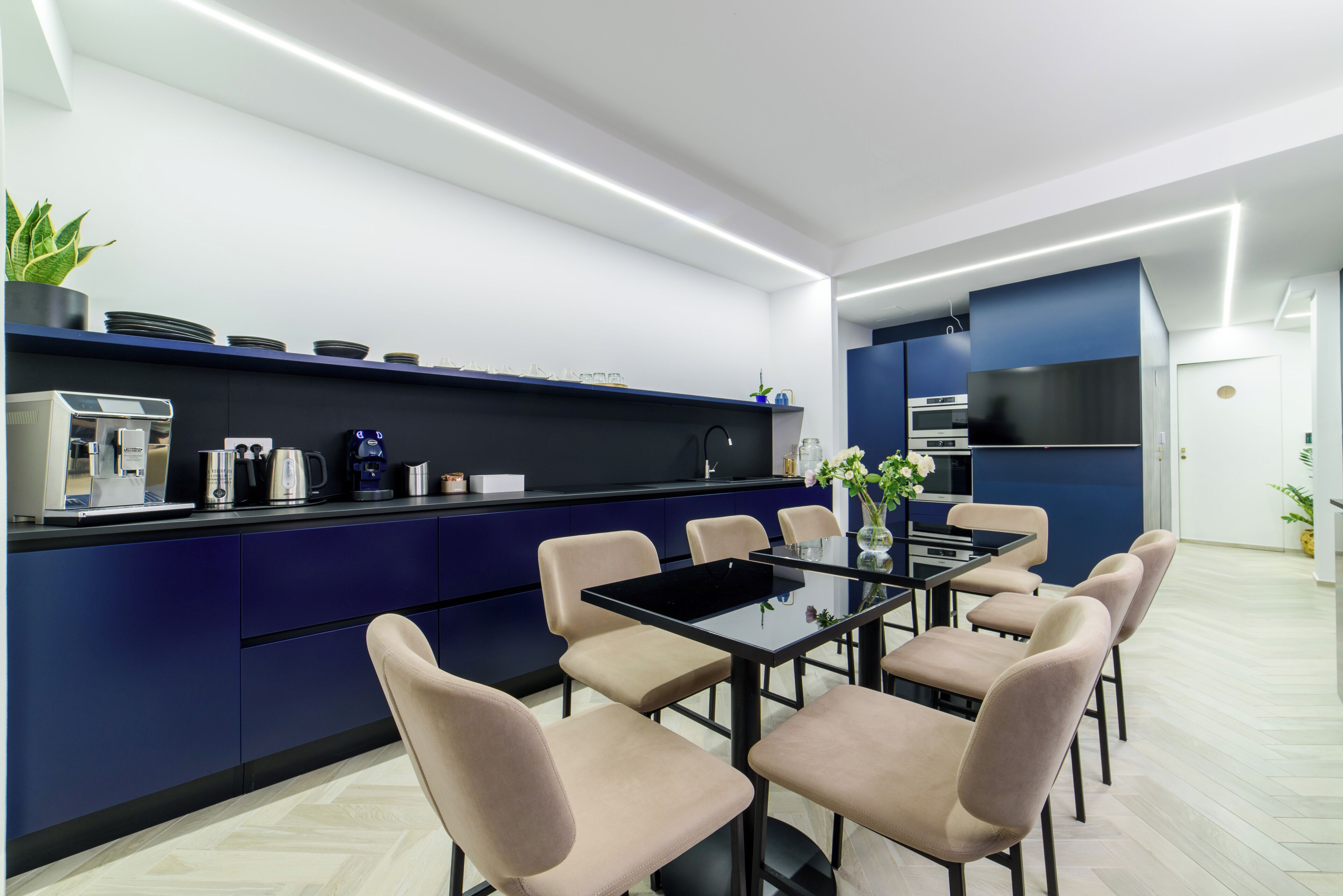 Une cuisine moderne dotée d’un îlot central, d’appareils électroménagers intégrés et d’un coin repas avec des chaises et une table.