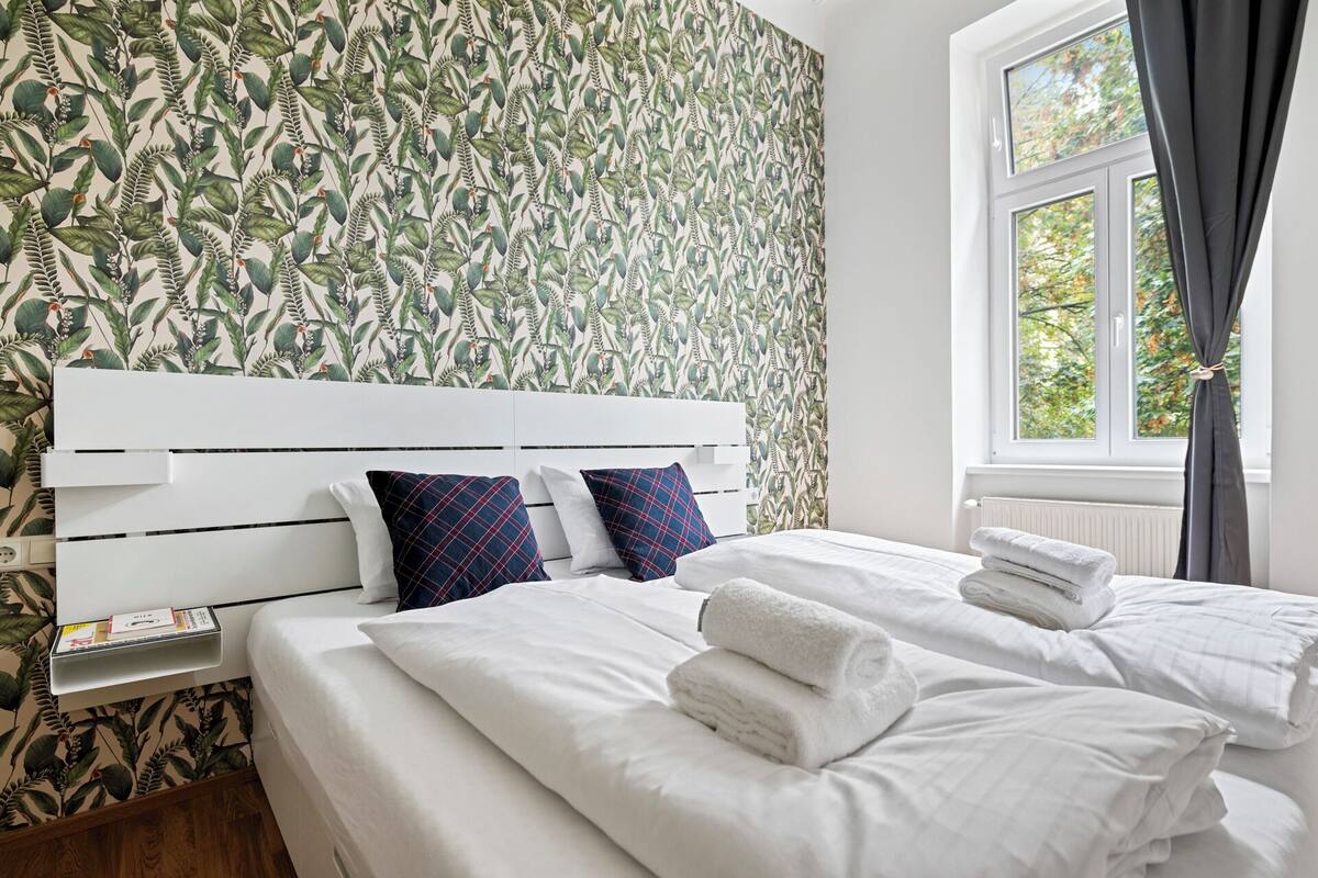 Ein Hotelzimmer mit Bett, weißem Kopfteil und einem Fenster mit Vorhängen.