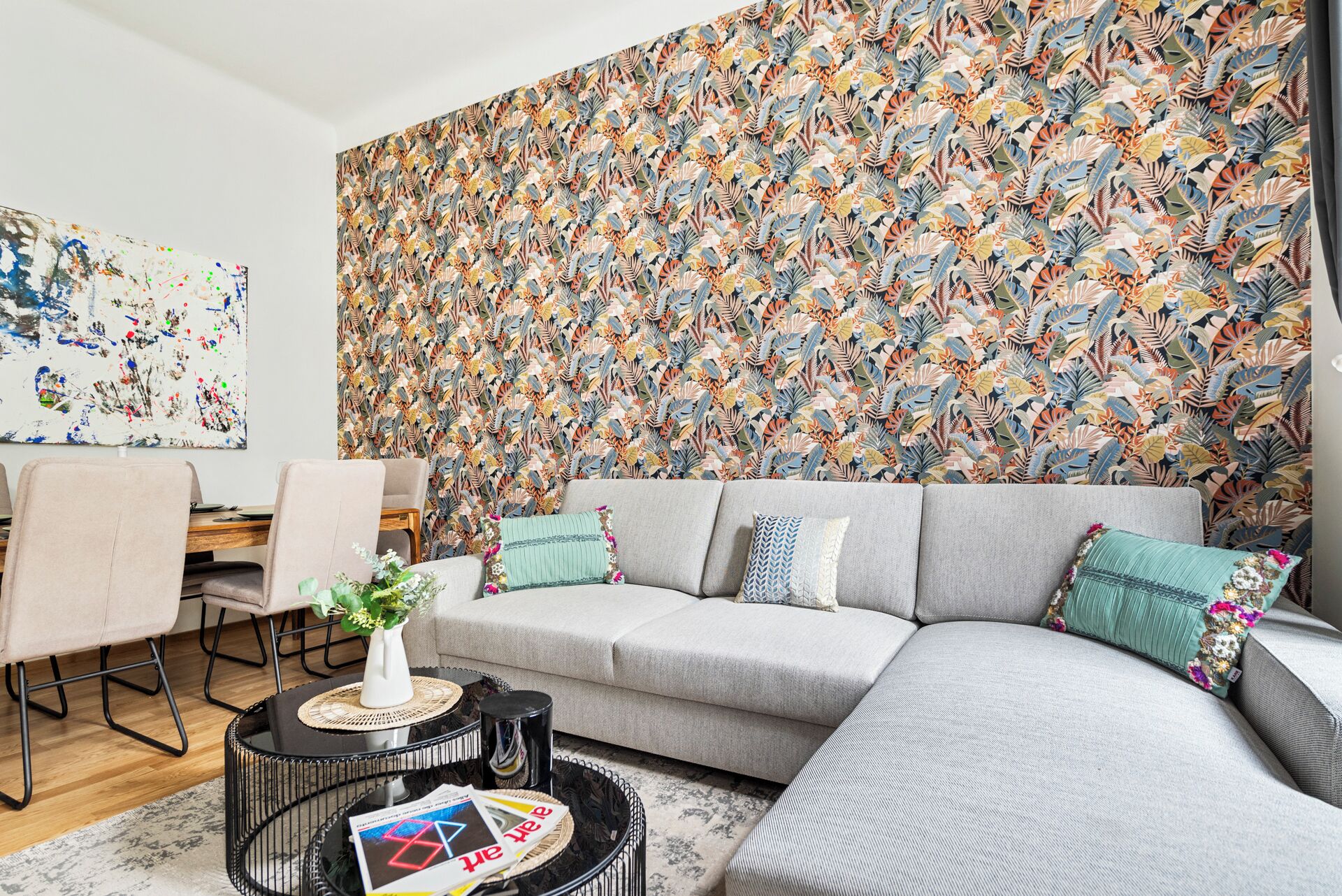 A modern living room with a grey sectional sofa, a coffee table with magazines, and a patterned wallpaper.