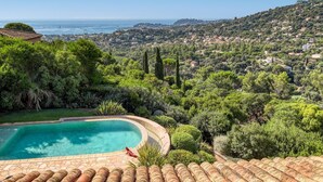 A pool surrounded by lush greenery and a view of a coastal town. - Villa Alouette, Sea view, swimming pool, air conditioning (Cavalaire-sur-Mer)