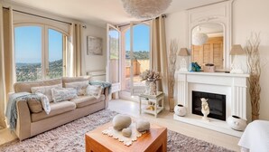 A spacious living room with a beige sofa, a fireplace, and a view of the countryside. - Villa Alouette, Sea view, swimming pool, air conditioning (Cavalaire-sur-Mer)