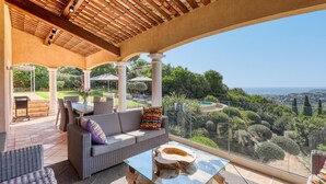 A covered outdoor seating area with a view of a pool and landscape. - Villa Alouette, Sea view, swimming pool, air conditioning (Cavalaire-sur-Mer)