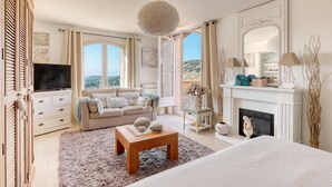 A spacious living room with a large window, a fireplace, a television, and a cozy seating area. - Villa Alouette, Sea view, swimming pool, air conditioning (Cavalaire-sur-Mer)