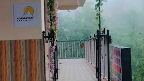 Entrada de un hotel con un letrero que dice "HIMALAYAN SERENITY", un camino cubierto y una entrada con puerta de reja.