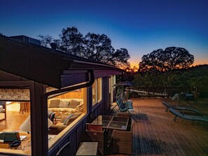 Una terraza acogedora con un sofá, sillas, una mesa de comedor y vistas al atardecer.