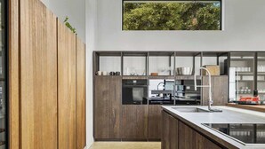 A modern kitchen with wooden cabinets, a large window, and a view of greenery. - Juniper Presents: Fab Vacay Home, Pool, Walk to Lake Michigan Beach (Michigan City)