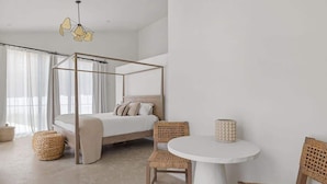 A bedroom with a four-poster bed, wicker chairs, a round table, and a hanging light fixture. - Juniper Presents: Fab Vacay Home, Pool, Walk to Lake Michigan Beach (Michigan City)