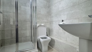 A modern bathroom with a glass shower enclosure, a white toilet, and a sink. - Stay Near Heathrow! Pristine, Convenient & Only 5 Mins to the Terminals (Staines)