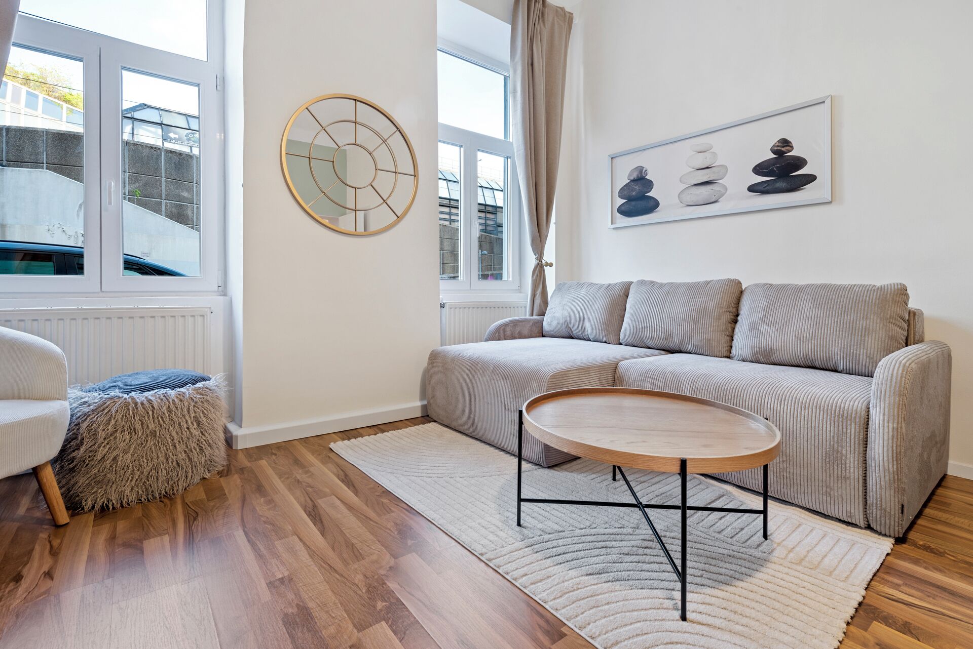 Ein Wohnzimmer mit einer Couch, einem runden Couchtisch, einem Teppich und einem Wandbild.