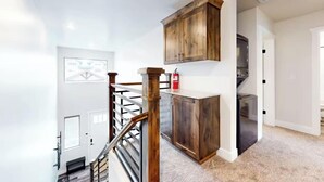 A modern kitchen with wooden cabinets, a stainless steel refrigerator, and a staircase leading to another level.