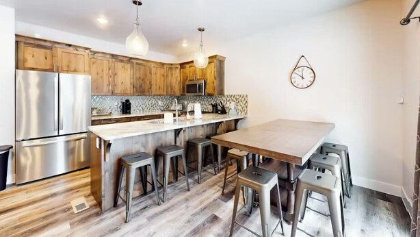 A modern kitchen with wooden cabinets, stainless steel appliances, and a large island with bar stools.