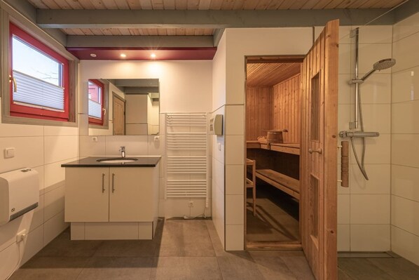 A compact bathroom with a sink, mirror, and shower.