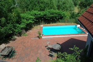 Una piscina rettangolare con rivestimento blu, circondata da un patio in mattoni e un pontile in legno.