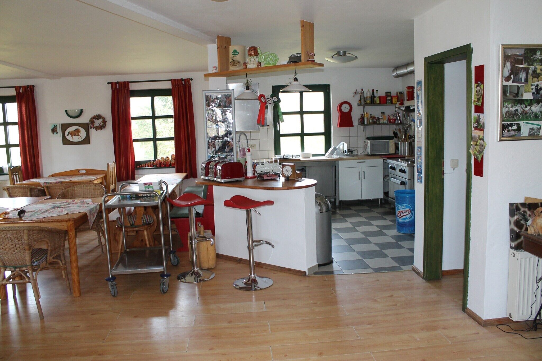 Una cocina con isla central, suelo de madera y zona de comedor con mobiliario de mimbre.