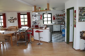 A kitchen with a central island, wooden flooring, and a dining area with wicker furniture.