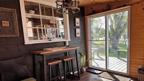 Una habitación acogedora con un banco de madera, una mesita pequeña y un ventanal con vistas a una terraza.
