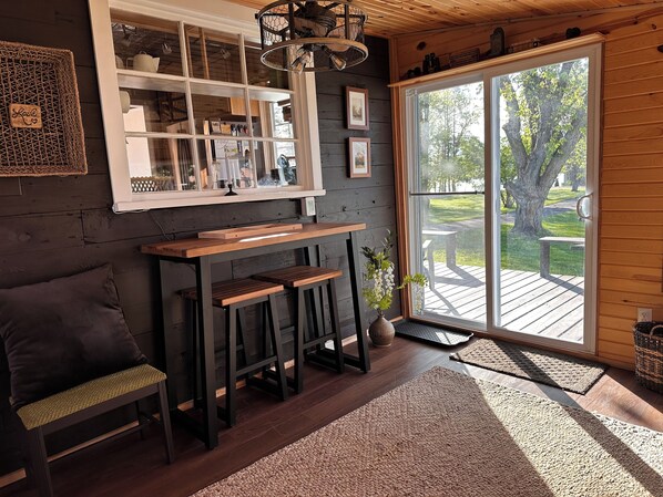 Una habitación acogedora con un banco de madera, una mesita pequeña y un ventanal con vistas a una terraza.