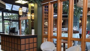 A reception area with a wooden reception desk, two modern chairs, and a large window with a view of the outdoors.