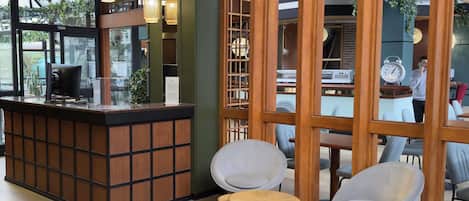 A reception area with a wooden reception desk, two modern chairs, and a large window with a view of the outdoors.