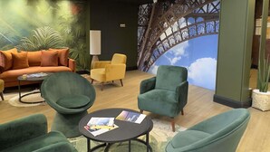 A lounge area with green upholstered chairs, a sofa, and a table with magazines.