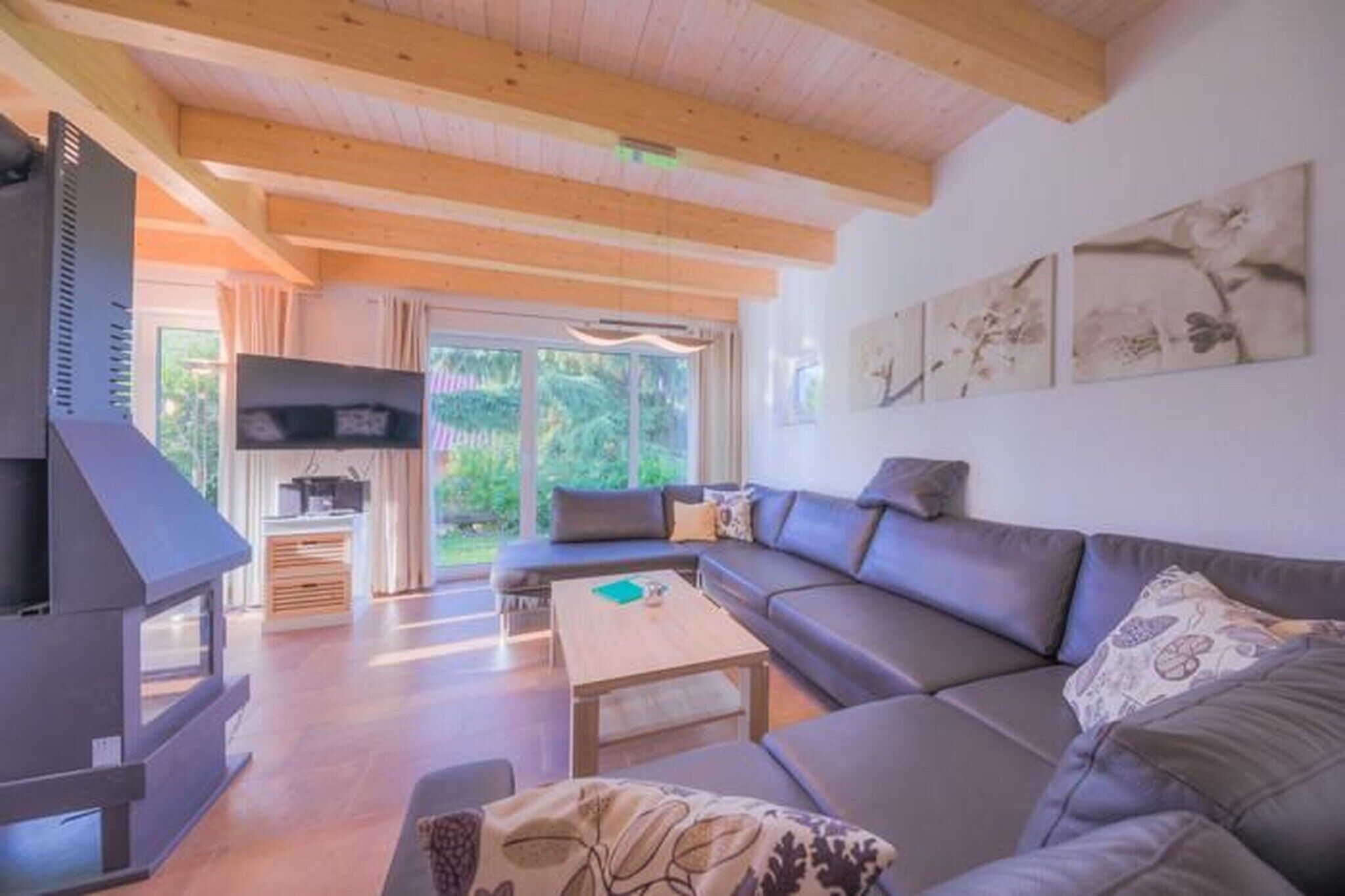 Ein modernes Wohnzimmer mit einem großen Ecksofa, Holzboden und einem Fernseher.
