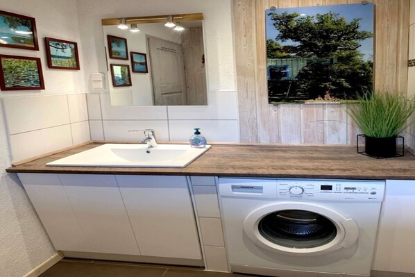 Une cuisine compacte équipée d’un évier, d’un lave-vaisselle et d’un lave-linge.