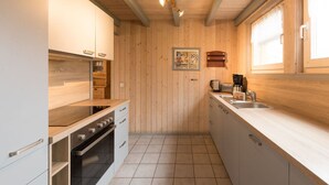 Una cocina moderna con paredes de madera, un lavamanos de acero inoxidable y un horno empotrado.