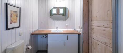 A compact bathroom with a wooden vanity, a toilet, and a mirror above the sink.