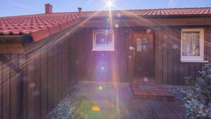 En træhytte med tegltag, en lille veranda og et vindue.