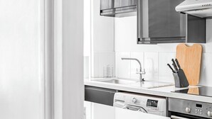 A modern kitchen with a stainless steel range hood, a dishwasher, and an oven.