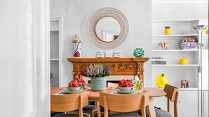 A dining area with a wooden table, chairs, a fireplace, and a bookshelf.