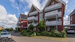A multi-story building with balconies and a parking area. - Appartement im Ferienpark in Rechlin (Rechlin)