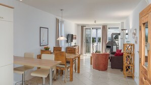 A modern living room with a dining area, a fireplace, and a view through a glass door. - Appartement im Ferienpark in Rechlin (Rechlin)