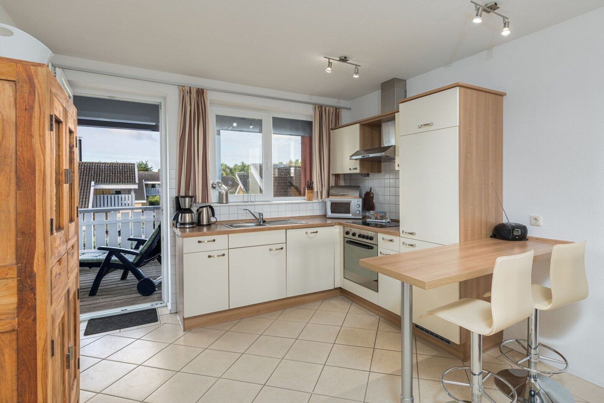 Eine kleine Küche mit Holztisch, zwei Barhocker und Blick auf die Terrasse.