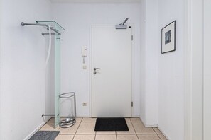 A small, clean bathroom with a glass shower enclosure, a white door, and a black doormat.