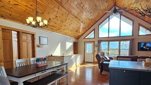 Une cuisine spacieuse avec un plancher en bois, un coin repas avec une table et des chaises, et une grande baie vitrée.