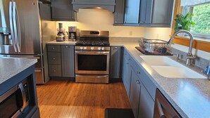 Une cuisine moderne avec un plafond en bois, des appareils électroménagers en acier inoxydable et des armoires grises.