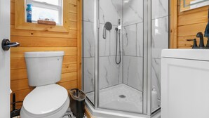 Une salle de bain comprenant des toilettes, une douche avec une porte en verre et un lavabo.