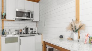 Une cuisine moderne avec des meubles blancs, un four à micro-ondes encastré et un plan de travail en marbre.