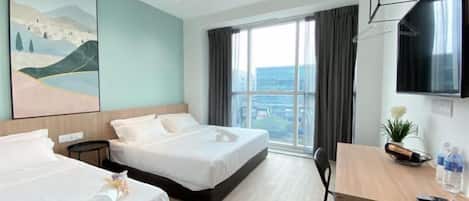 A hotel room with two beds, a desk, a TV, and a large window with a city view.