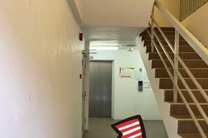 Un pasillo con una escalera, una puerta y un cartel en la pared.