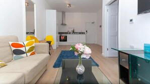 A modern living room with a sofa, a glass coffee table, and a vase of flowers. - Flat 308 One bedroom Apartment (Smethwick)