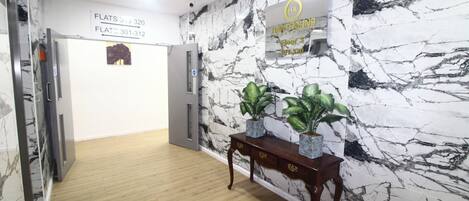 Corredor com paredes de mármore, piso de madeira e placa indicando a localização dos apartamentos 301 a 312.