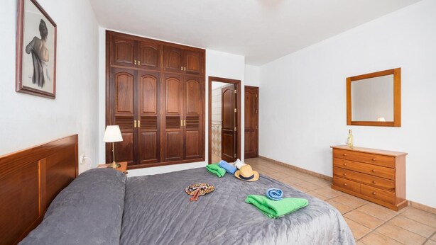 Une chambre à coucher comprenant un lit, une armoire, une commode, un miroir et un tableau encadré accroché au mur.