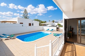 A swimming pool with lounge chairs, a barbecue area, and a view of neighboring buildings. - Villa Diama - Three Bedroom Villa, Sleeps 6 (Puerto Calero)