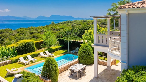 Un área de piscina con sillones reclinables, una mesa y una pérgola con vistas a un paisaje montañoso.